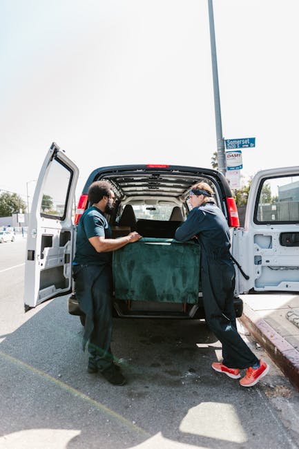 The image shows a scene with a damaged white van that has been overturned onto its side, revealing its rusted and weathered exterior. Inside the open side door, the interior appears dark and empty, wi